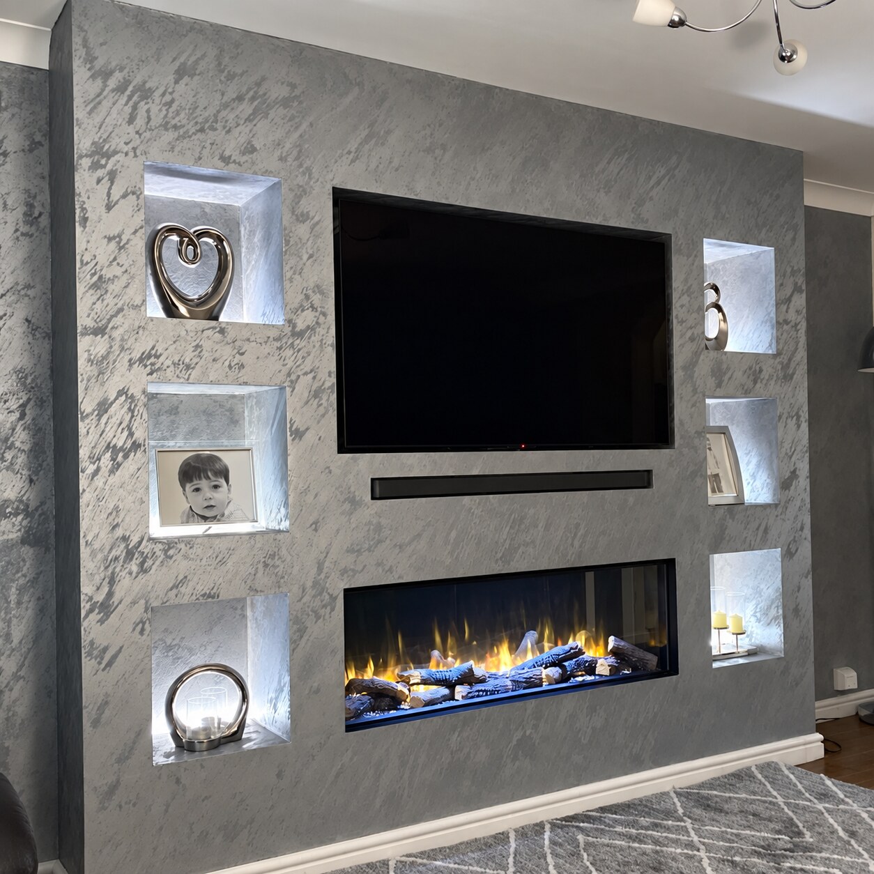 Completed grey polished plaster media wall with lit niches, television and fireplace